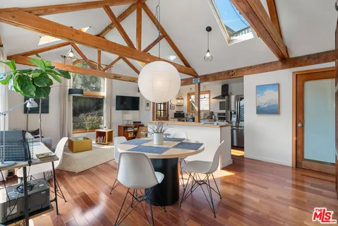 a dining room with wooden floor a chandelier a wooden table and chairs