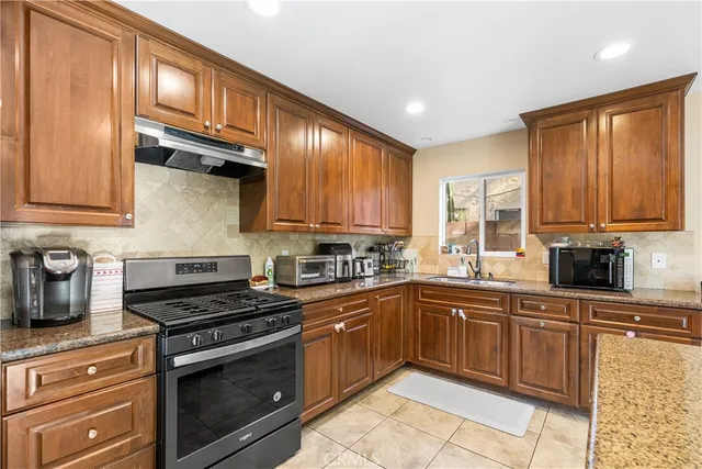 a kitchen with stainless steel appliances granite countertop a stove top oven a sink a dining table and chairs