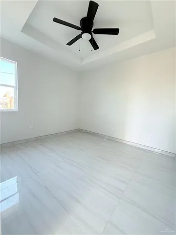 an empty room with a ceiling fan and window