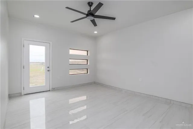 an empty room with windows and ceiling fan