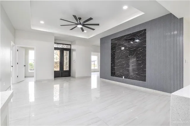 a view of a livingroom with a chandelier fan and windows
