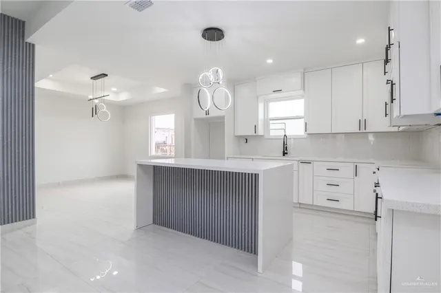 a kitchen with kitchen island white cabinets stainless steel appliances and a window