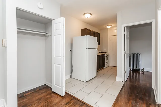 a view of a refrigerator in kitchen and an empty room with wooden floor windows