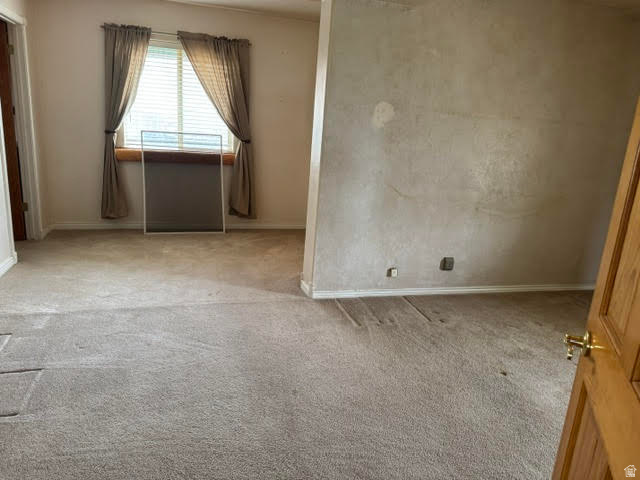 1124 Washam Road Green River, WY 82938 - Photo 24 of 35 Carpeted room with a window featuring blinds and drapes, a partial wall, and a wooden door with brass hardware