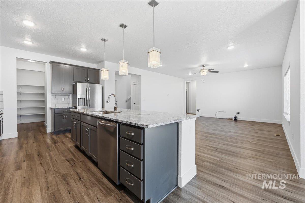 148 Homesteaders Street Middleton, ID 83644 - Photo 45 of 45 Kitchen featuring light stone counters, stainless steel appliances, an island with sink, open floor plan, and pendant lighting