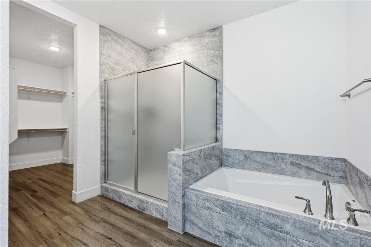 148 Homesteaders Street Middleton, ID 83644 - Photo 24 of 45 Bathroom featuring a walk in closet, a stall shower, dark wood finished floors, a bath, and a textured ceiling