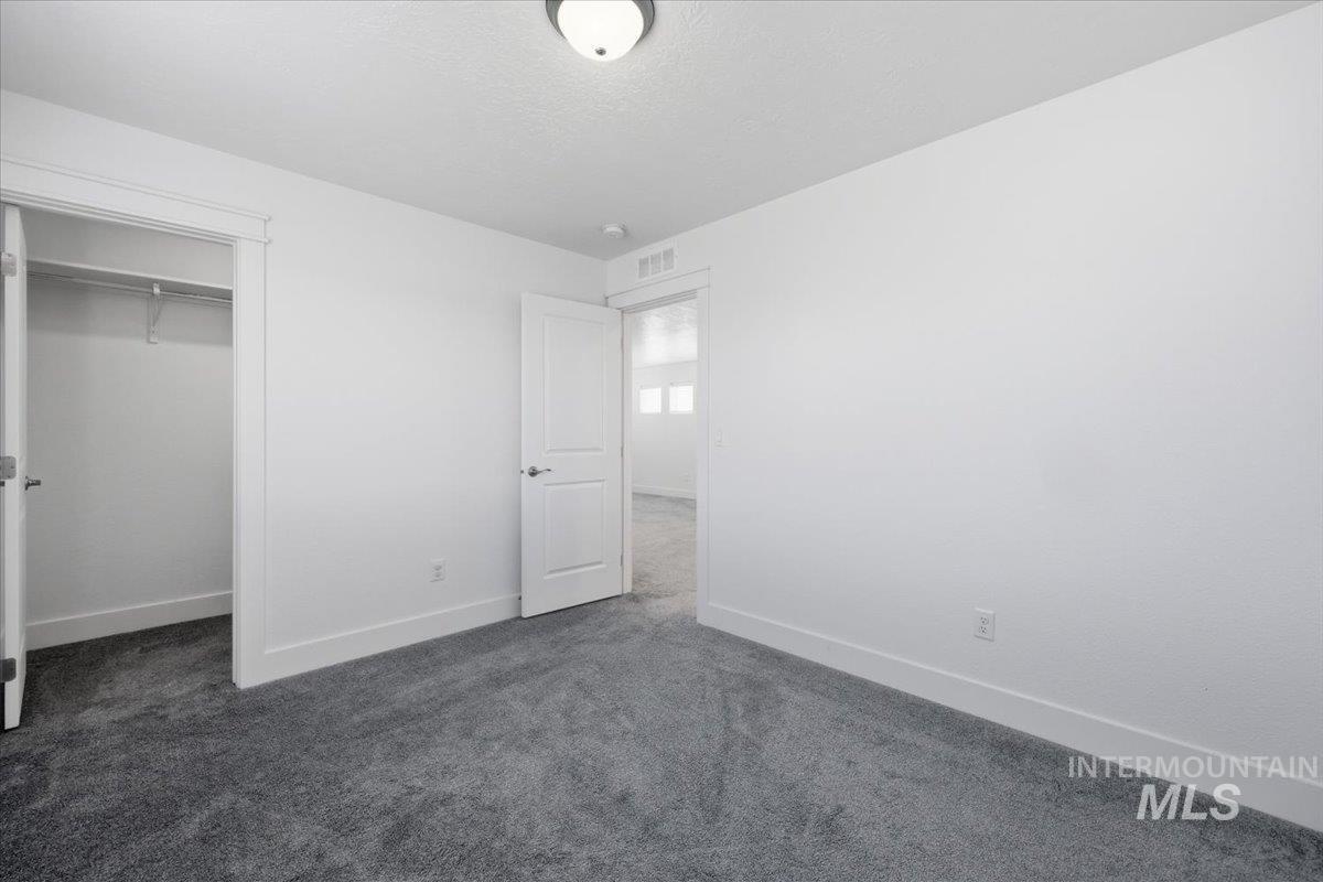 148 Homesteaders Street Middleton, ID 83644 - Photo 30 of 45 Unfurnished bedroom featuring dark carpet and a walk in closet