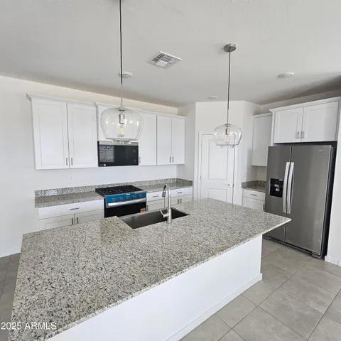 a kitchen with stainless steel appliances granite countertop a sink a refrigerator a stove and white cabinets