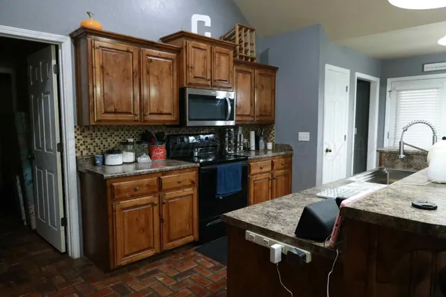 a kitchen with kitchen island granite countertop a sink stove and refrigerator