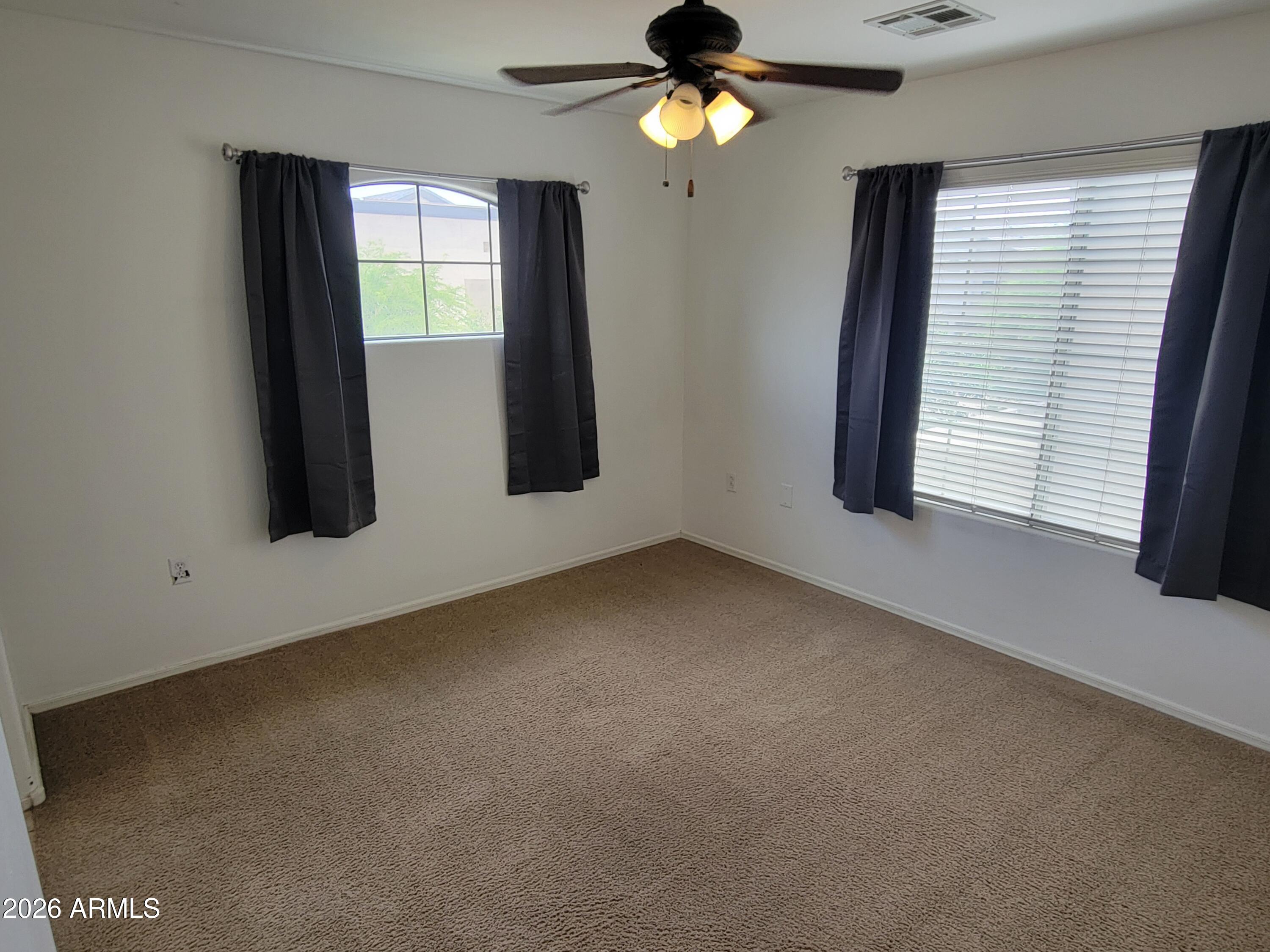 1350 South Greenfield Road, Unit 1053 Mesa, AZ 85206 - Photo 11 of 25 an empty room with windows and fan