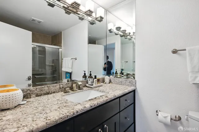 a bathroom with a granite countertop sink a mirror and shower