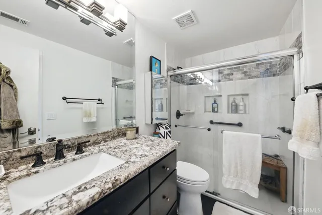 a bathroom with a granite countertop sink toilet and shower