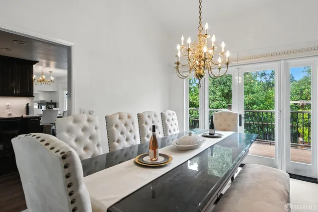 a view of a dining room with furniture a chandelier and large windows