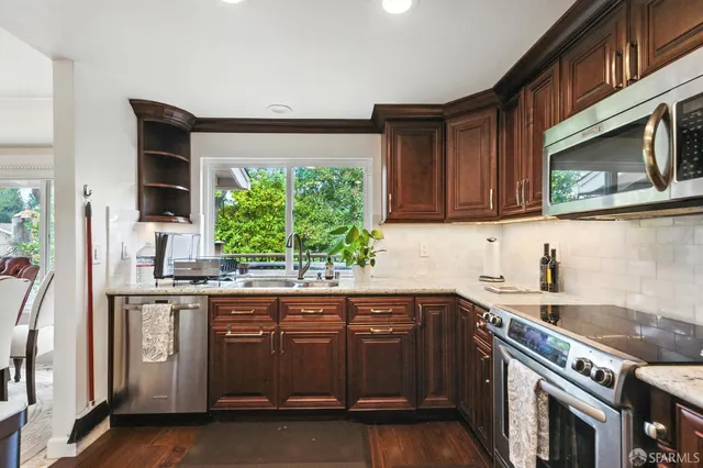 a kitchen with stainless steel appliances granite countertop a stove a sink dishwasher and a microwave oven with wooden floor