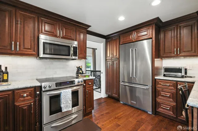 a kitchen with granite countertop wooden cabinets stainless steel appliances and a window