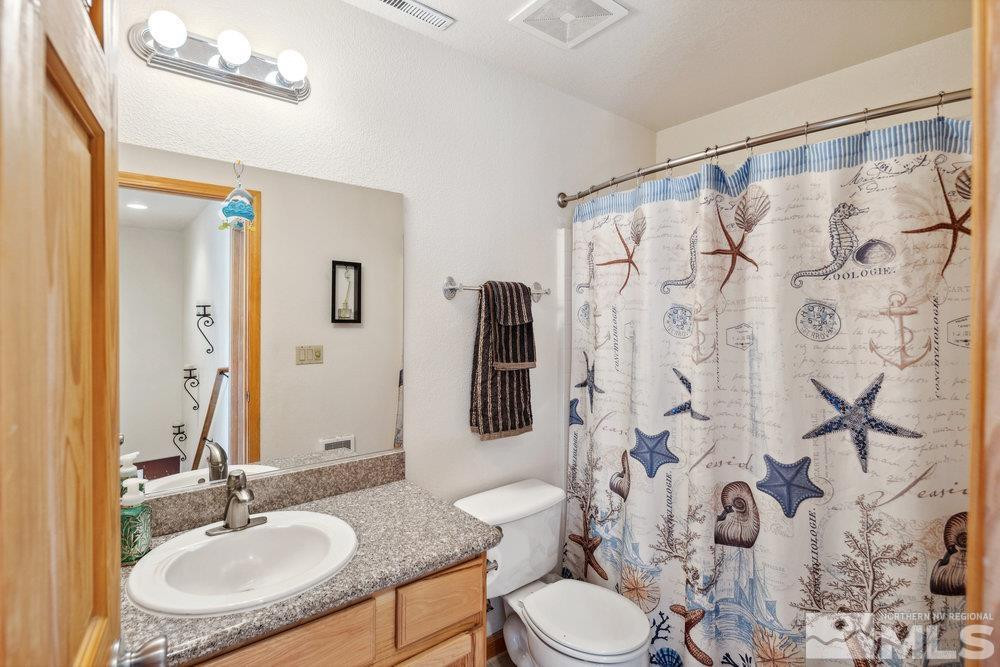 2045 Flint Road Reno, NV 89521 - Photo 21 of 33 a bathroom with a granite countertop sink toilet a mirror a shower and a sink
