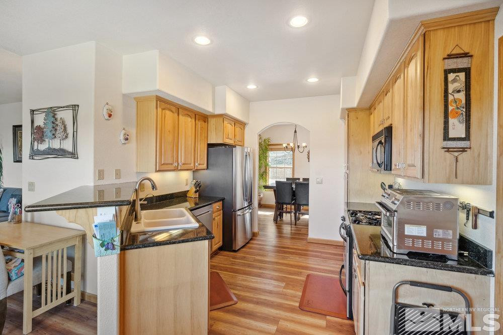 2045 Flint Road Reno, NV 89521 - Photo 6 of 33 a kitchen with stainless steel appliances granite countertop a stove top oven a sink dishwasher a dining table and chairs with wooden floor