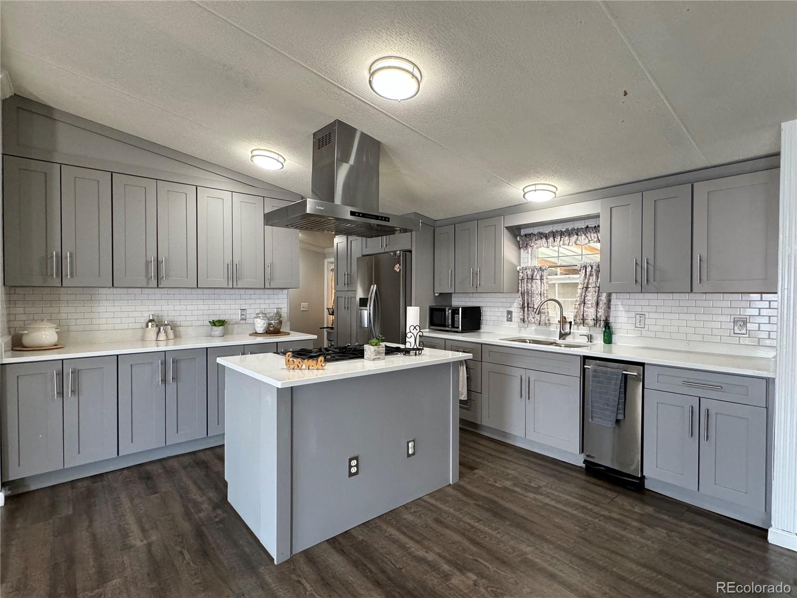 1921 Quintero Street Aurora, CO 80011 - Photo 6 of 18 a kitchen with a sink cabinets wooden floor and stainless steel appliances