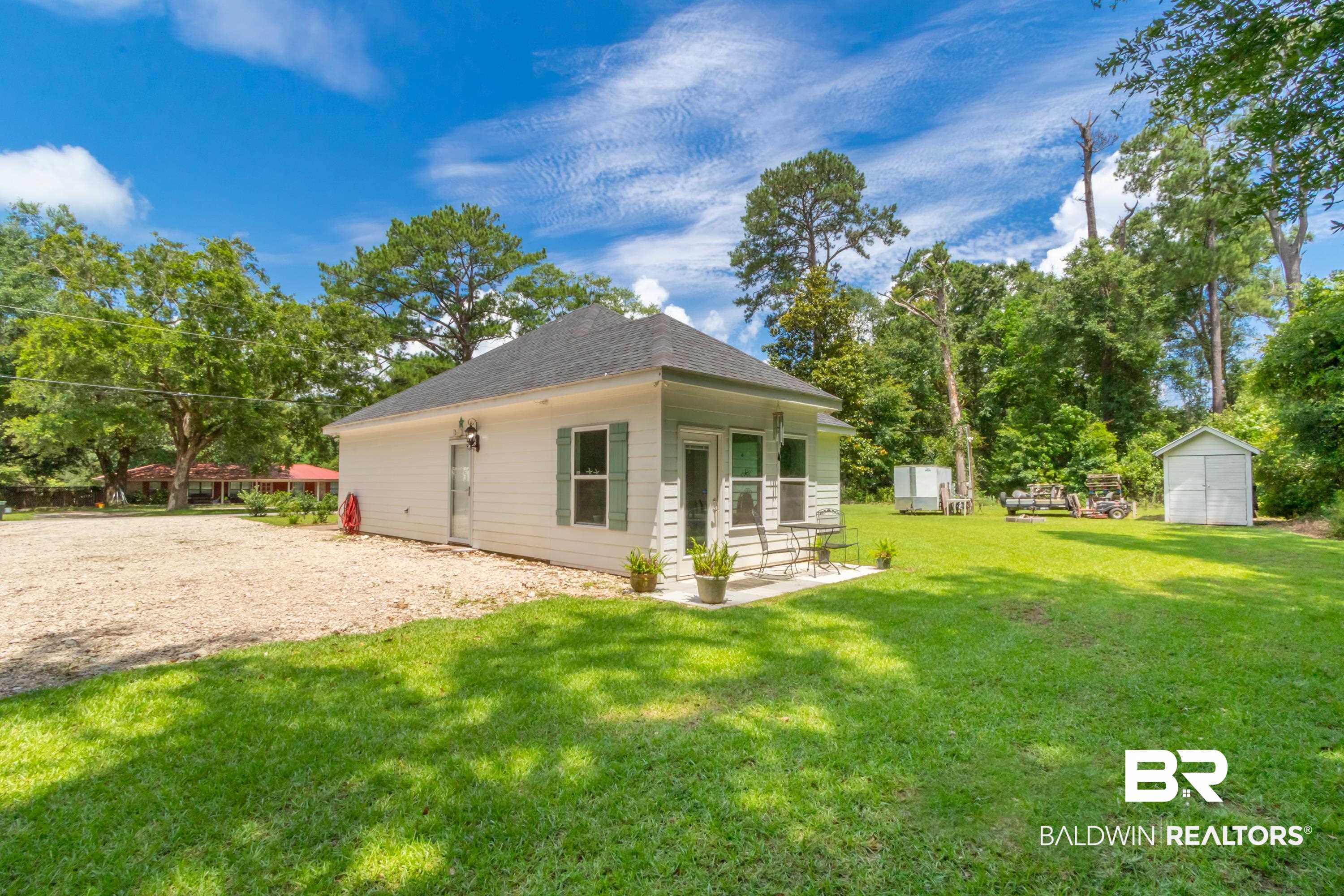 7472 Coopers Landing Road Foley, AL 36535 - Photo 33 of 40 White siding exterior with a dark shingle roof, offering a covered patio space and a spacious gravel area