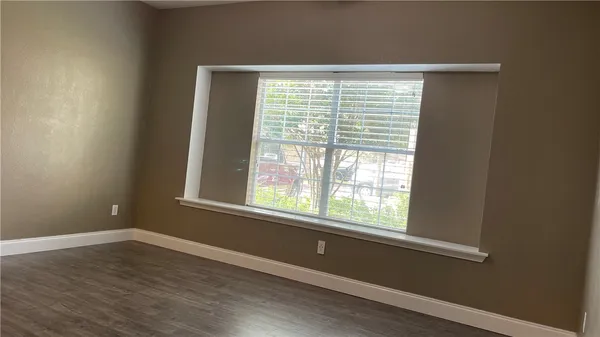 a view of an empty room with wooden floor and a window