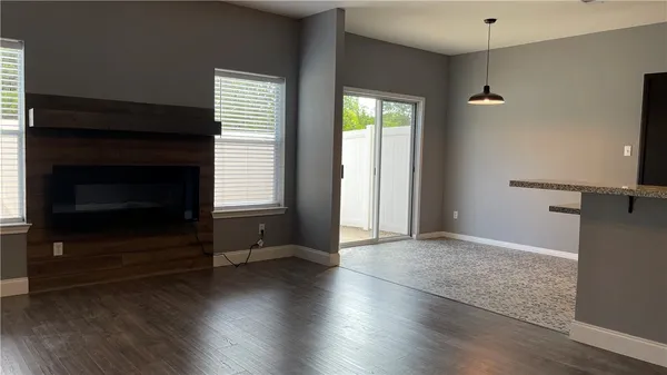 an empty room with wooden floor fireplace and windows