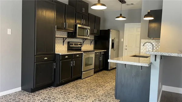 a kitchen with stainless steel appliances kitchen island granite countertop a refrigerator and a sink