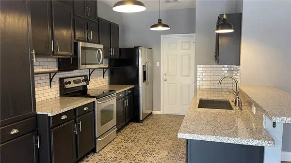 a kitchen with granite countertop stainless steel appliances a sink stove and refrigerator