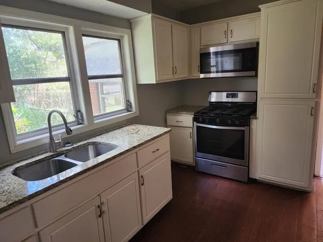 a kitchen with stainless steel appliances granite countertop a sink stove and microwave