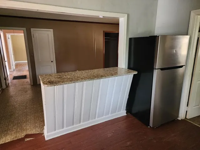 a kitchen with refrigerator and wooden floor