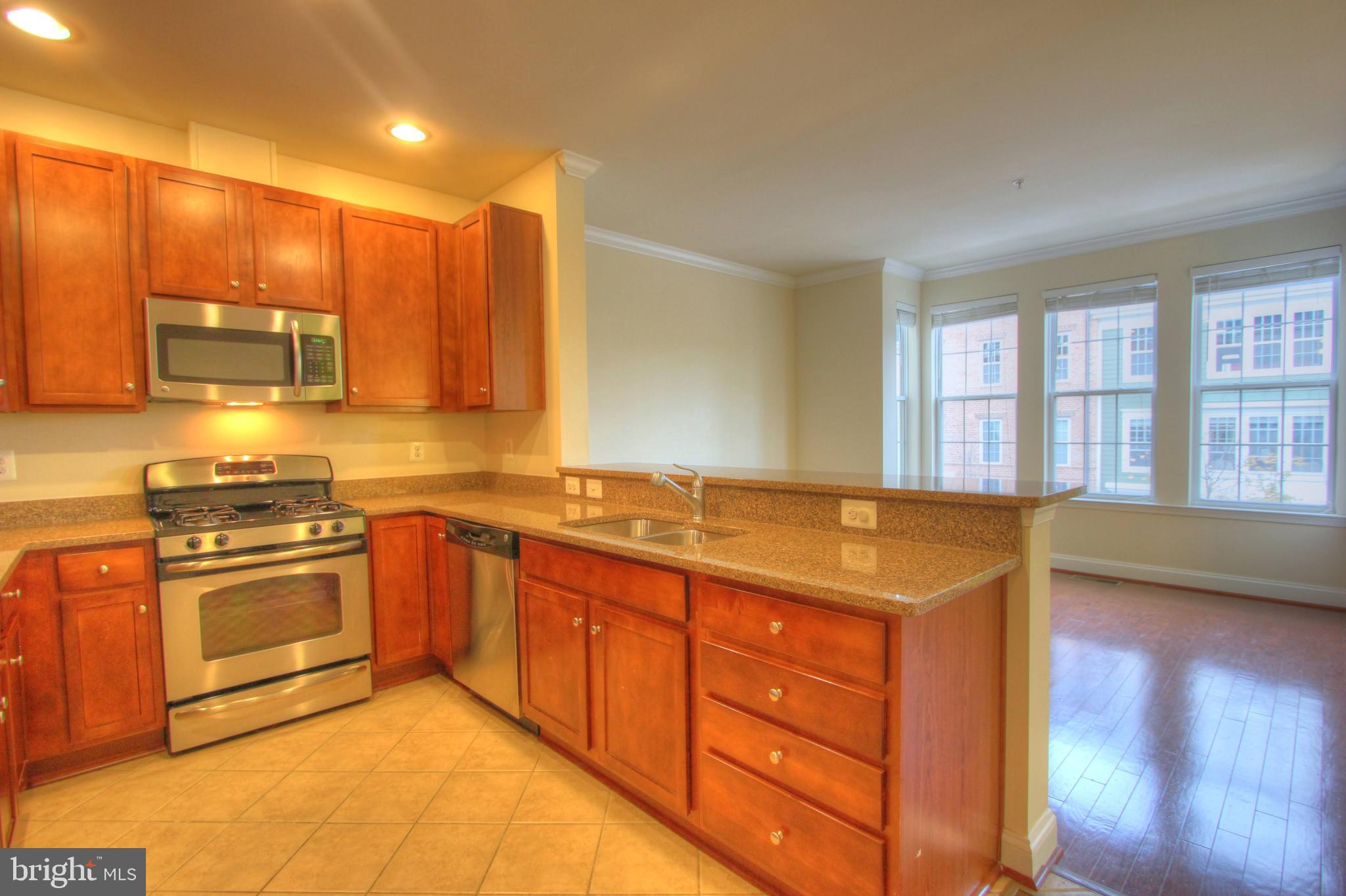 11205 Chase Street, Unit 63 Fulton, MD 20759 - Photo 7 of 22 a kitchen with stainless steel appliances granite countertop a stove a sink and a refrigerator