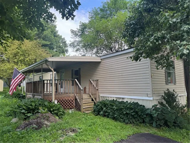 a white house with a small yard plants and large trees