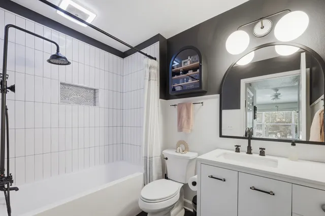 a bathroom with a toilet a sink a tub and mirror