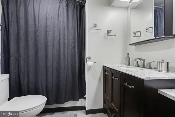 a bathroom with a granite countertop sink vanity mirror and toilet