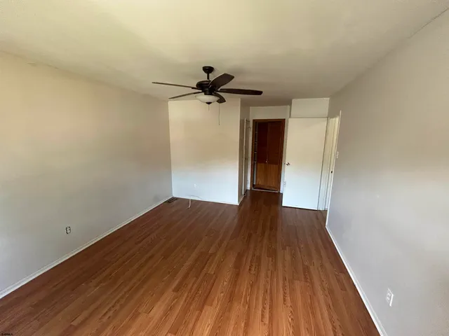 a view of empty room with wooden floor and fan