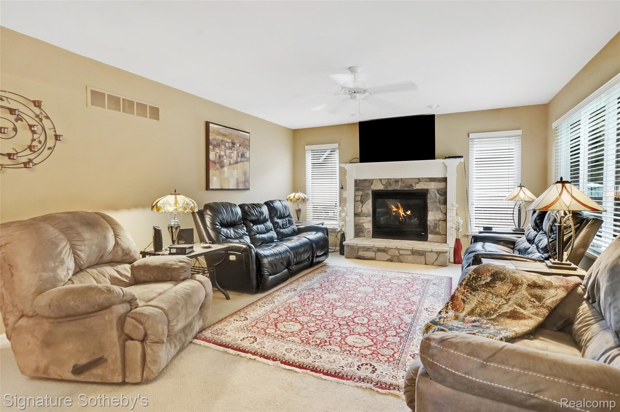 170 Fairhill Way Howell, MI 48843 - Photo 12 of 60 Family room featuring a stone surround gas fireplace, ceiling fan, and multiple windows for natural lighting
