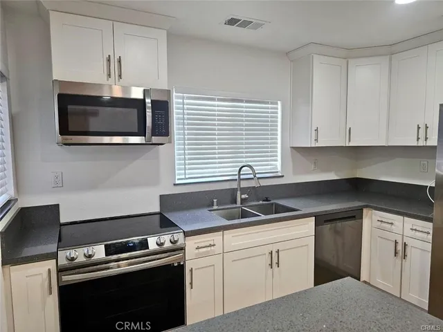 a kitchen with stainless steel appliances granite countertop a stove a sink a microwave a refrigerator and chairs