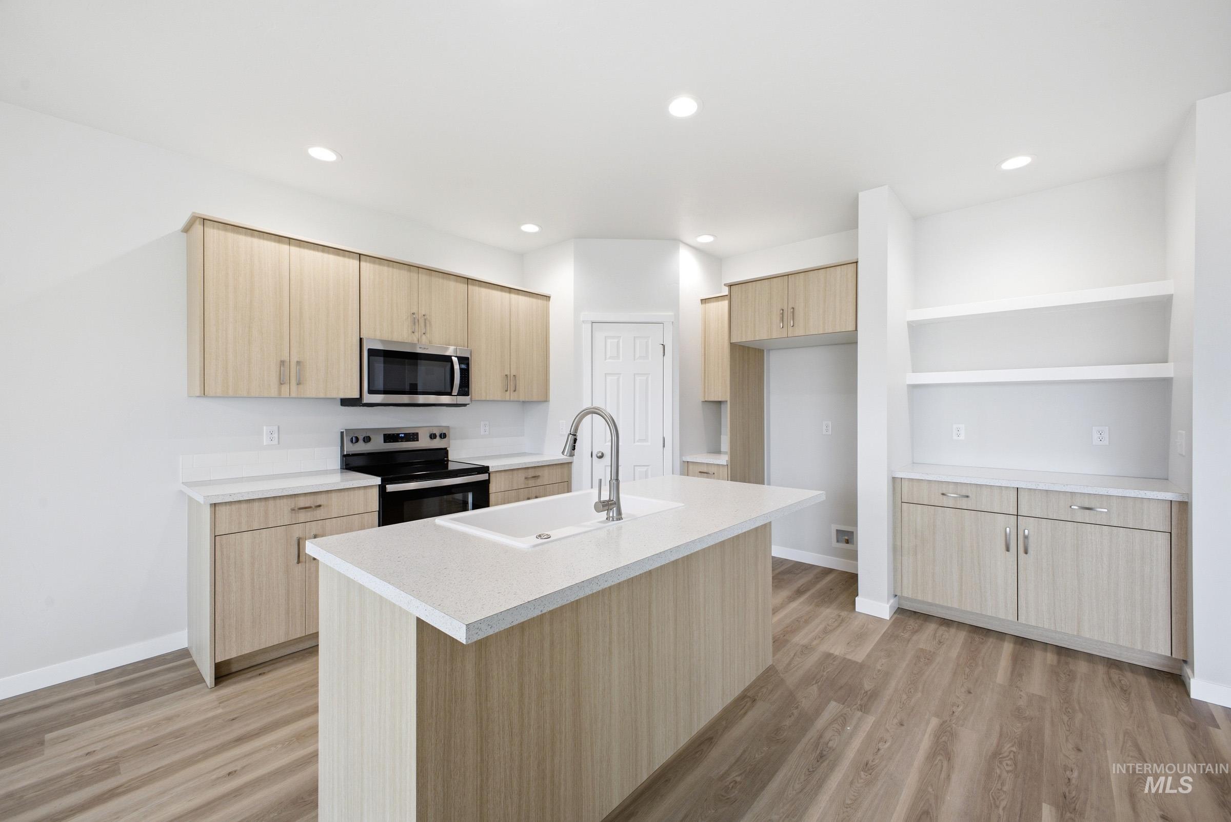 14104 Shiny Spruce Street Caldwell, ID 83607 - Photo 4 of 20 Modern kitchen featuring light wood-finish cabinetry, white countertops, and wood-finish flooring