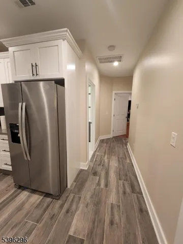 a view of a refrigerator in kitchen and an empty room