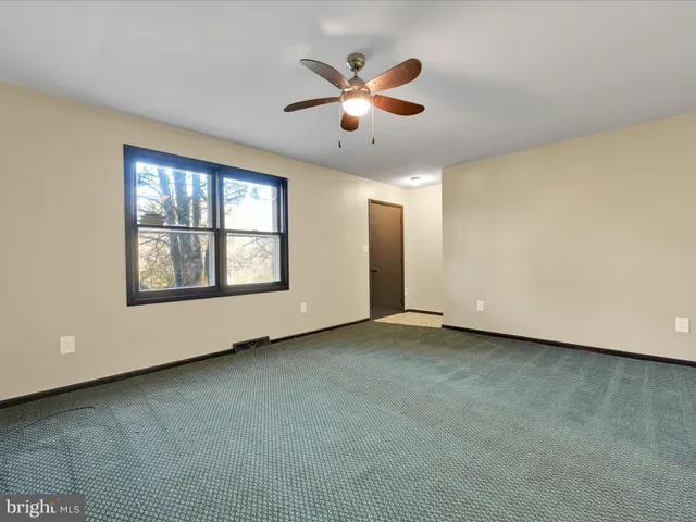 an empty room with ceiling fan and windows