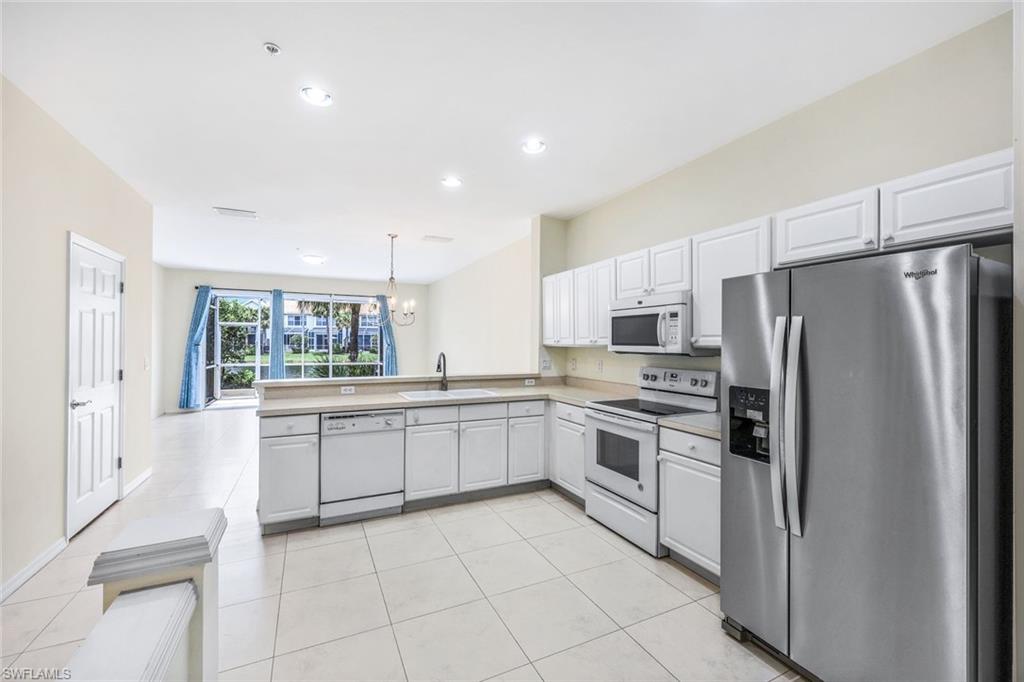 15612 Marcello Circle, Unit 158 Naples, FL 34110 - Photo 8 of 27 a large kitchen with white cabinets and stainless steel appliances