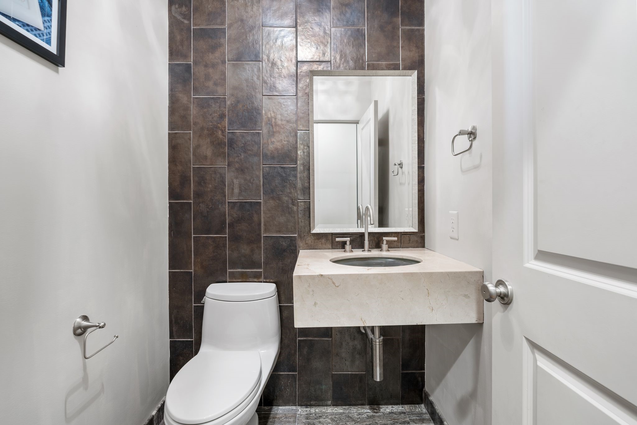 3934 Feagan Street Houston, TX 77007 - Photo 13 of 27 The second floor powder room is conveniently located just off the family room and feels elevated with its bold tile accent wall. A floating quartz countertop, framed mirror, and updated fixture give it a clean, modern look that's perfect for guests.