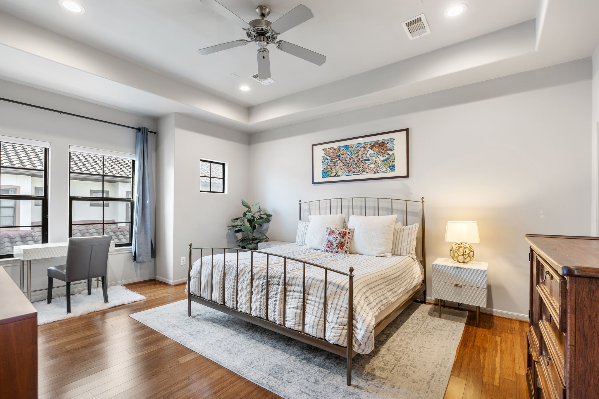 3934 Feagan Street Houston, TX 77007 - Photo 14 of 27 Privately positioned on the third floor, the primary bedroom feels like a true retreat with its tray ceiling, recessed lighting, and modern ceiling fan. The windows are finished with Hunter Douglas shades paired with drapery, offering both privacy and light control while keeping the space soft and elevated. Two walk in closets complete this suite with the storage everyone wants.