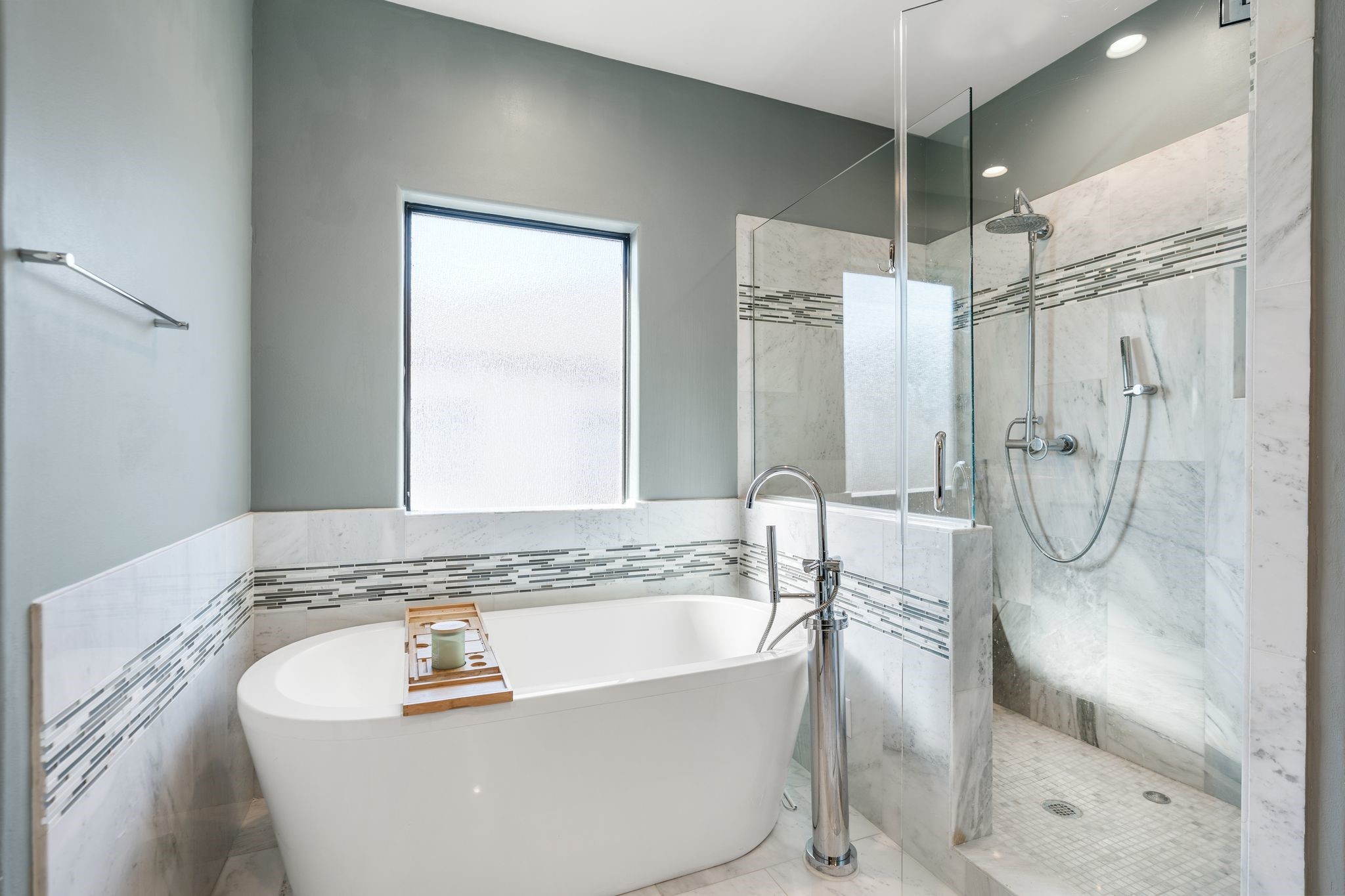 3934 Feagan Street Houston, TX 77007 - Photo 17 of 27 This angle shows the large soaking tub and the walk-in shower with frameless glass. The shower includes a rain shower head plus a handheld sprayer, and the shower walls and floor are finished in marble. A large window brings natural light while maintaining privacy.