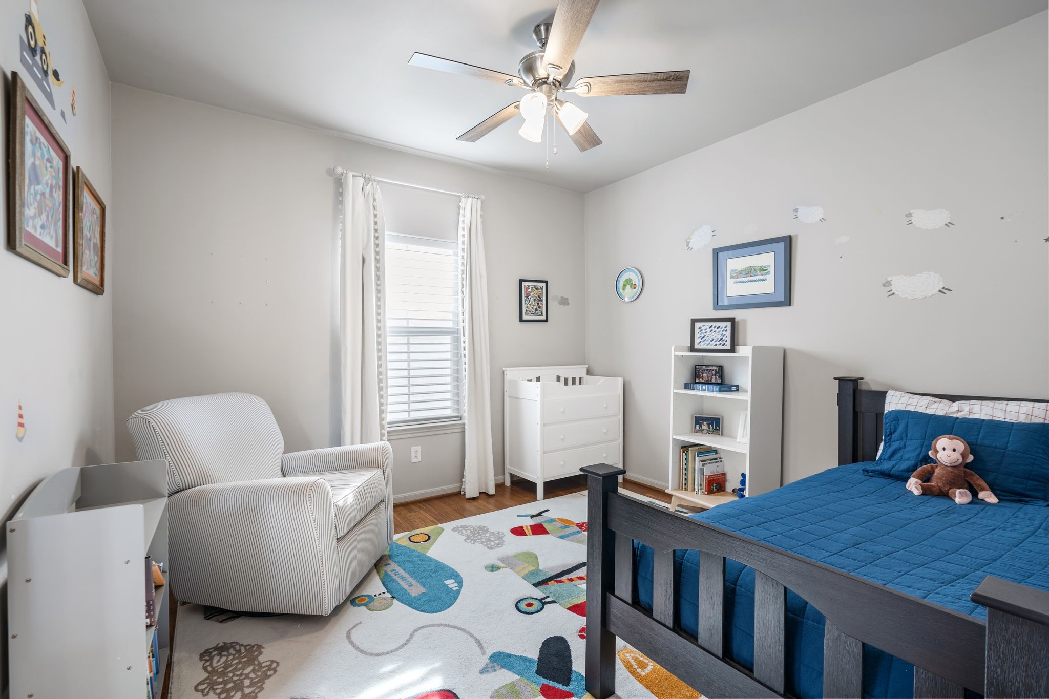 3934 Feagan Street Houston, TX 77007 - Photo 18 of 27 Third floor secondary bedroom with wood flooring, a ceiling fan and a large window that brings natural light. The window is finished with Hunter Douglas shades plus drapes. Plenty of wall space for a bed set up, dresser, or a small seating/ reading area. Note the decals of sheep can be removed.