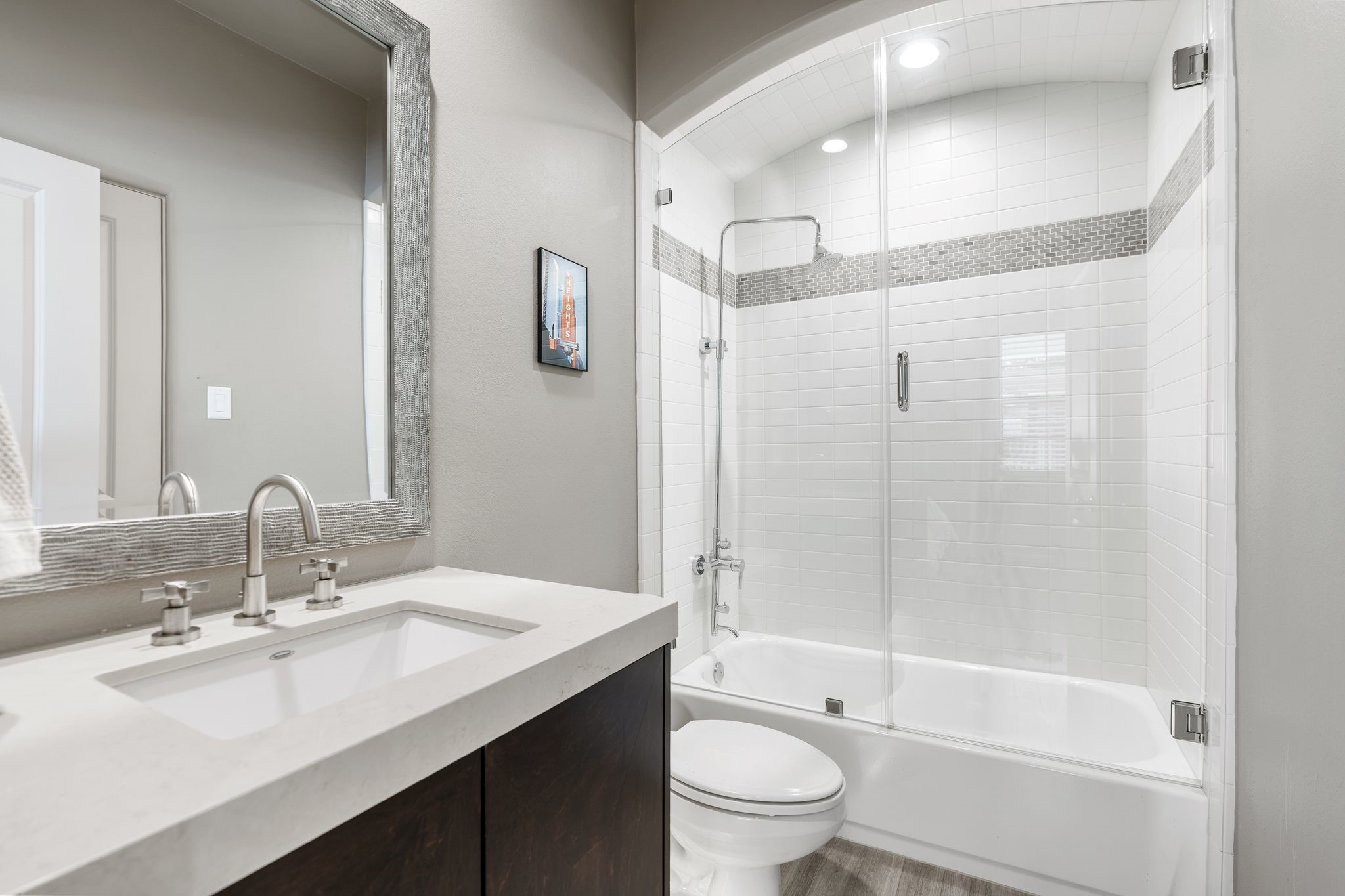 3934 Feagan Street Houston, TX 77007 - Photo 21 of 27 Guest bath with tile flooring, a marble countertop vanity, and a framed decorative mirror. Subway tile continues through the tub/shower surround, and there's also a separate door that opens out to the entryway for added convenience.