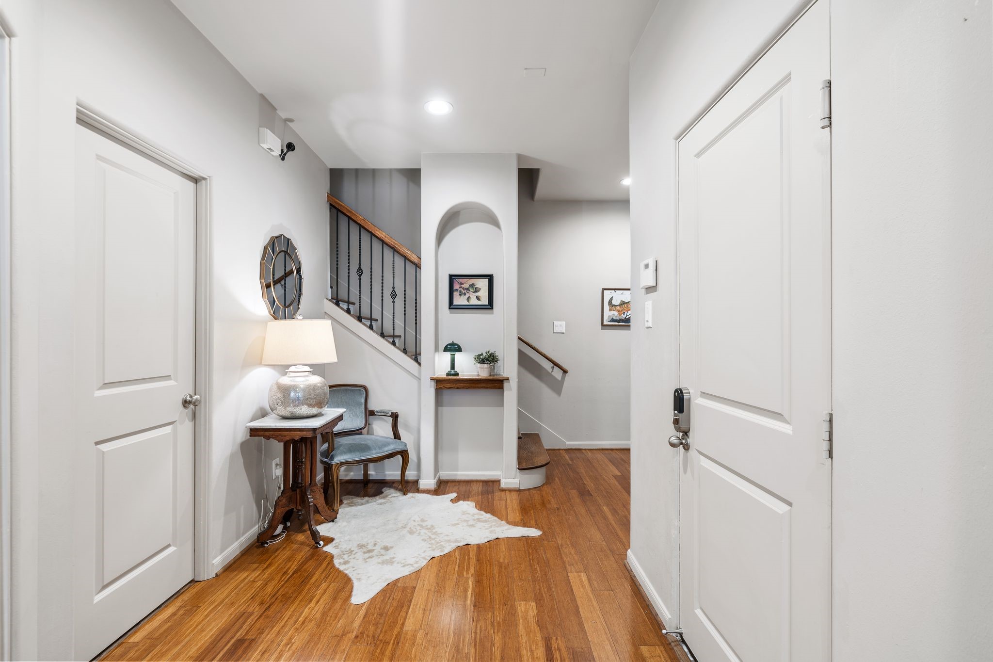 3934 Feagan Street Houston, TX 77007 - Photo 2 of 27 Welcome into a bright, inviting entry featuring rich hardwood floors and a statement wood front door with a glass insert. A curved art niche creates a perfect spot to showcase artwork or decor while the sightline to the wrought iron staircase adds instant character and a polished first impression.
