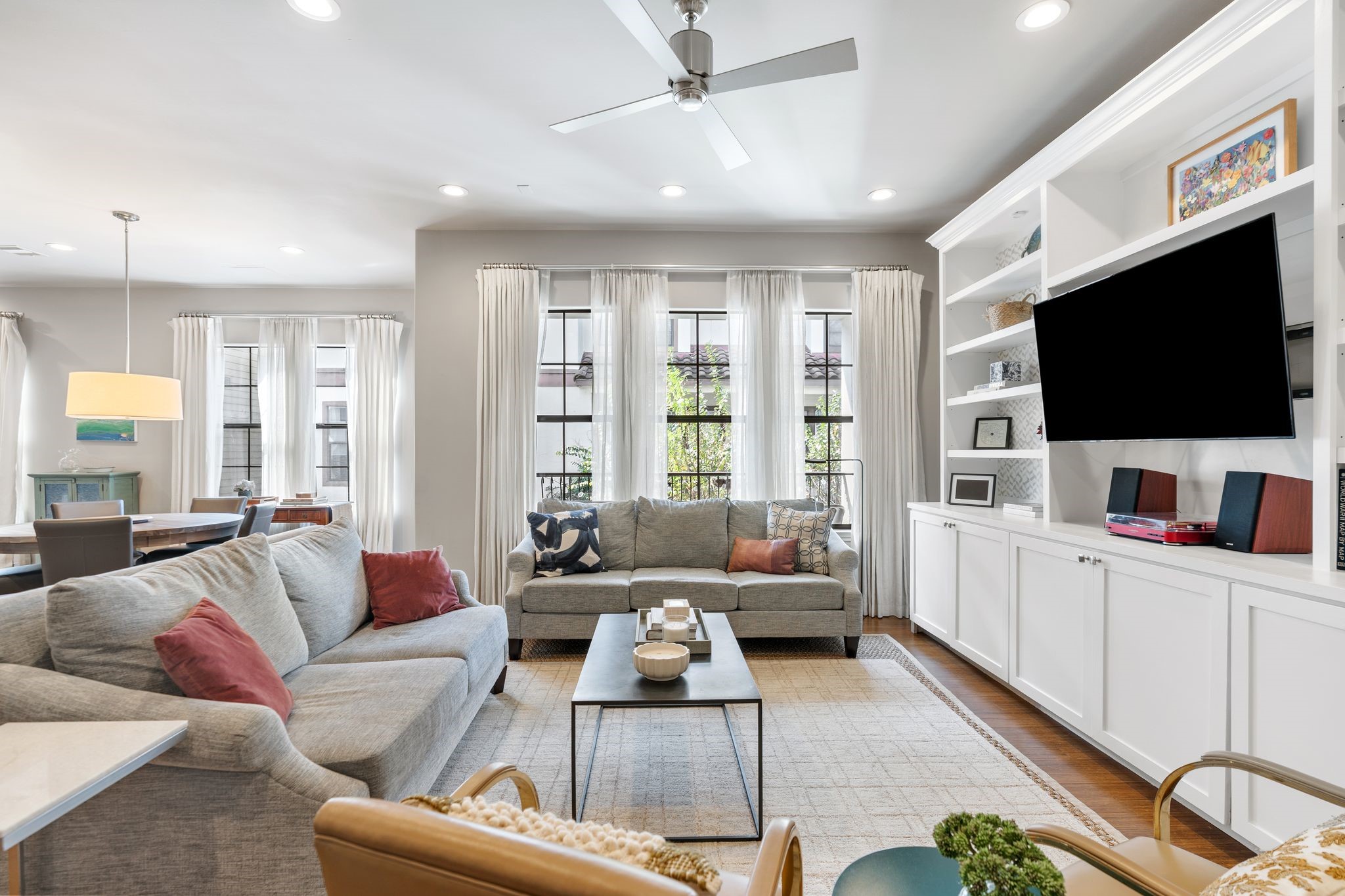 3934 Feagan Street Houston, TX 77007 - Photo 5 of 27 Wall to wall windows steal the show here– filling the family room with sunshine and serene treetop views. The drapes add a polished designer look, and the windows look out to the balcony for an easy indoor outdoor feel; a modern ceiling fan completes the space with a crisp contemporary touch.