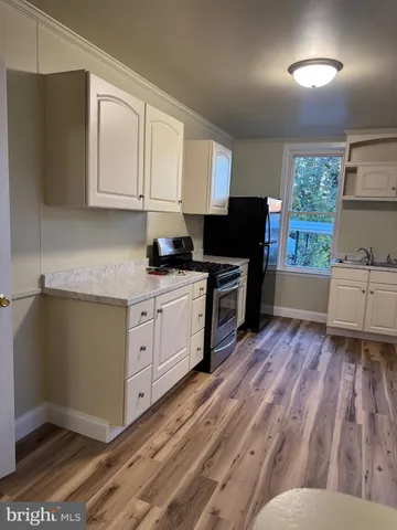 a kitchen with stainless steel appliances a stove top oven refrigerator a sink dishwasher and microwave with wooden floor