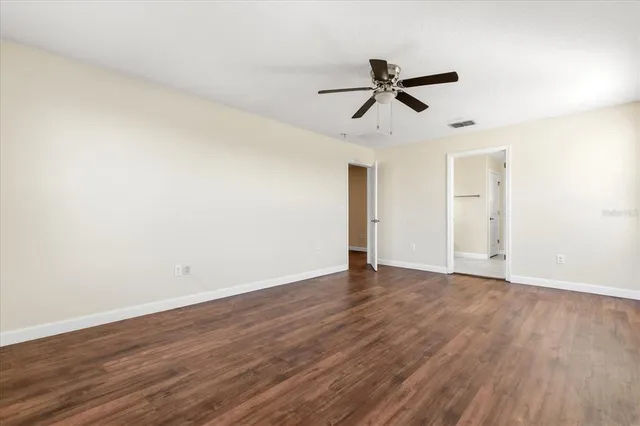 a view of empty room with wooden floor and ceiling fan