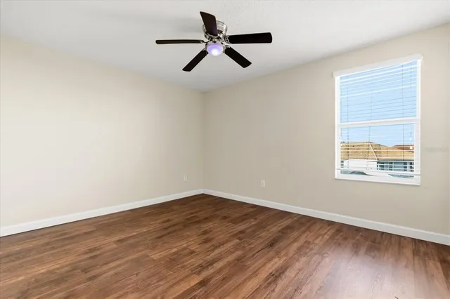 a view of empty room with wooden floor and fan
